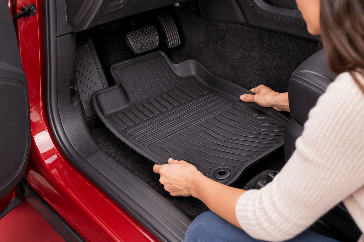 A woman's hands checking a removable car floor mat against an open car footwell, fit and coverage central.
